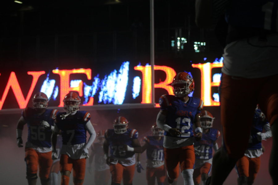 Bishop Gorman varsity football team running onto Fertitta Field.