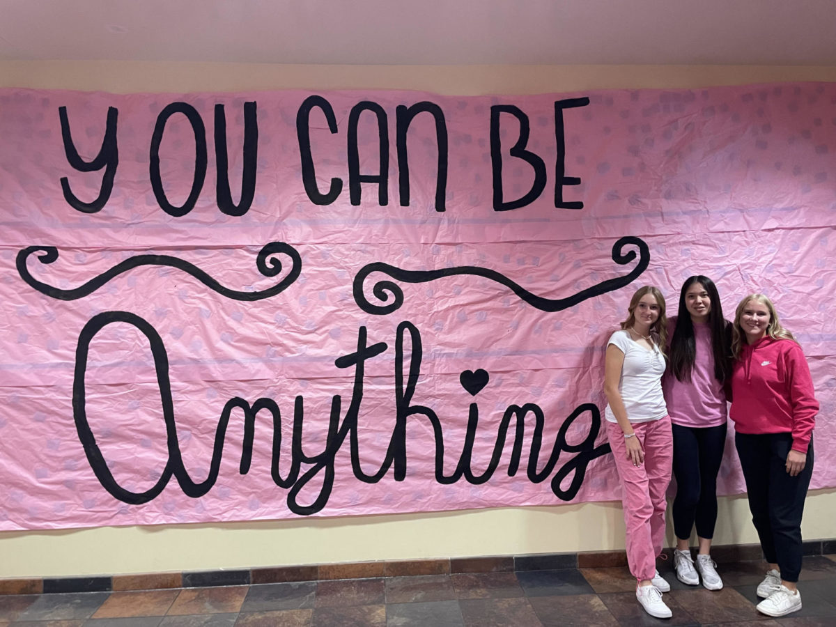 Sophomores Mackenzie Motzny, Karoline Watters, and Olivia Calloway posed by the You Can Be Anything poster. 