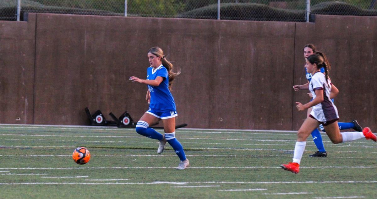 Tatum Manley '25 dribbling past Faith Lutheran defenders.