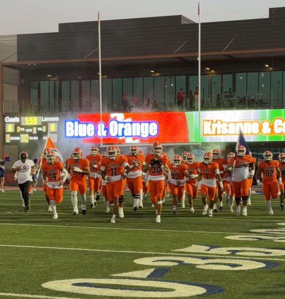 Varsity Football running out onto the field to take on Orange Luther. 