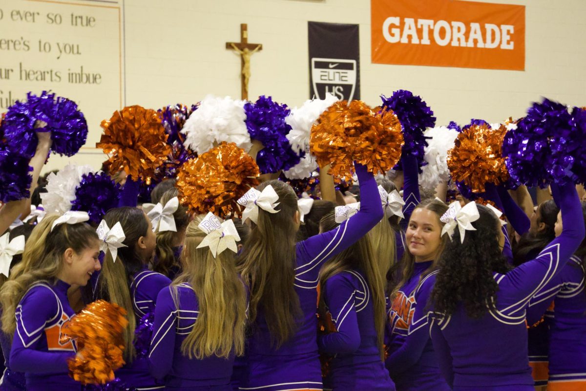 Cheerleaders cheering and waving their poms after singing the alma mater together.