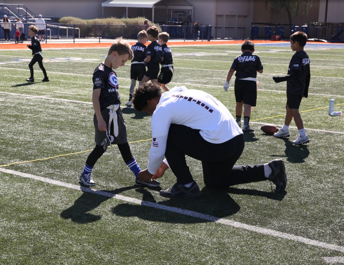 Jason Lawrence ‘29 helps player tie his shoe. 